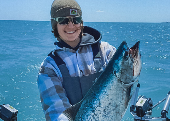 Fishing guide holding a caught fish on a boat.