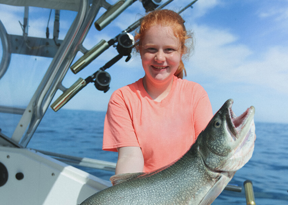 Child holding a caught fish on a boat.