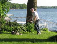 A man mowing his lawn with a manual push mower instead of a gas-powered machine.