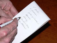 person writing a list with paper and pen